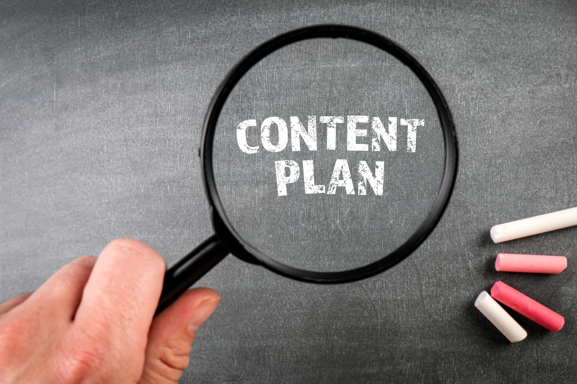 Content Plan. Magnifying glass on a dark chalkboard background